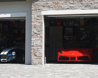 Red sports car parked inside a modern garage with stone walls.